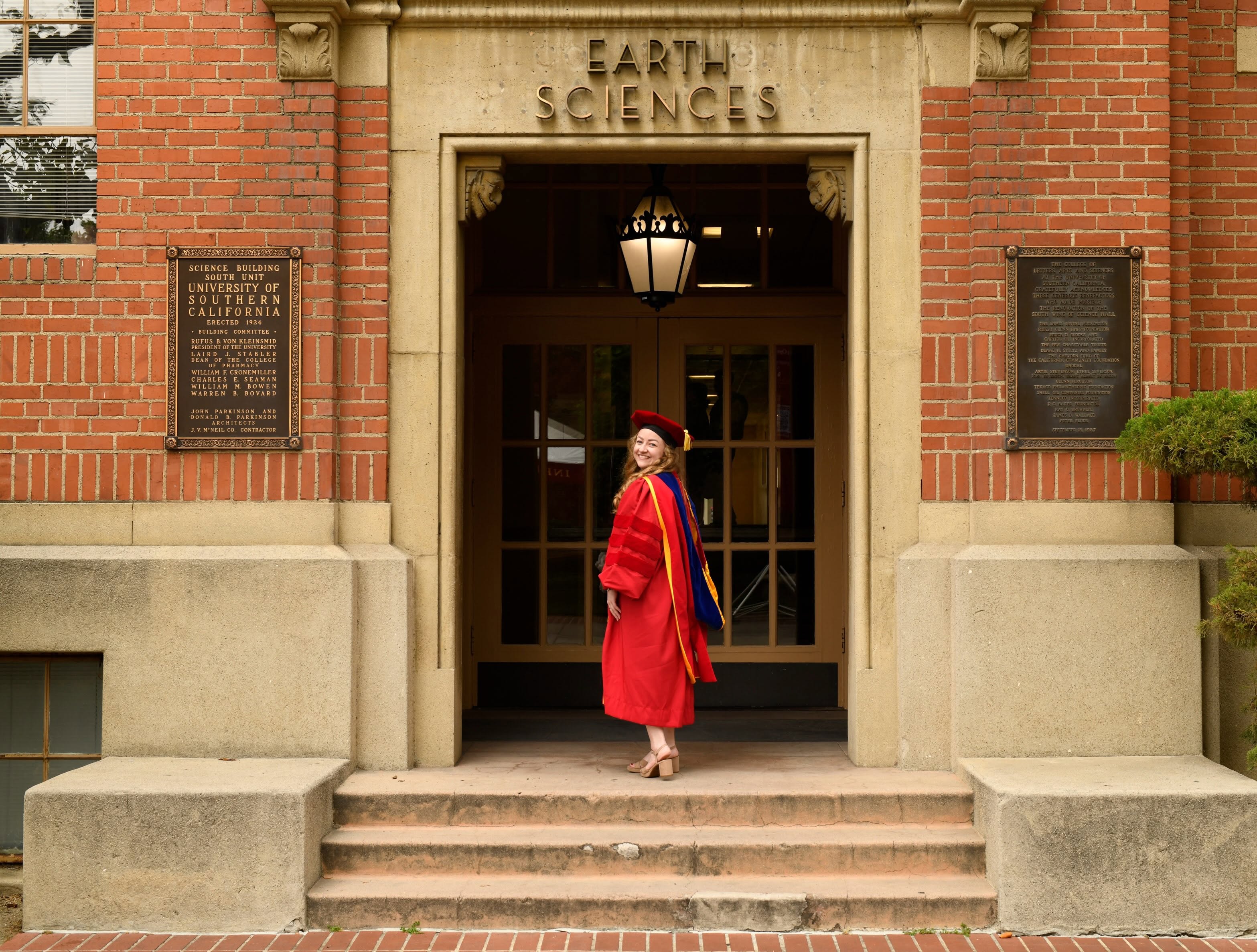 Brianna Birkel in doctoral graduation regalia outside the USC Earth Sciences building